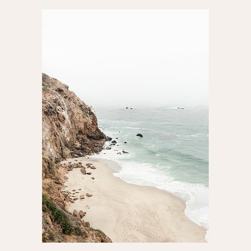 a picture of a beach with a cliff in the background