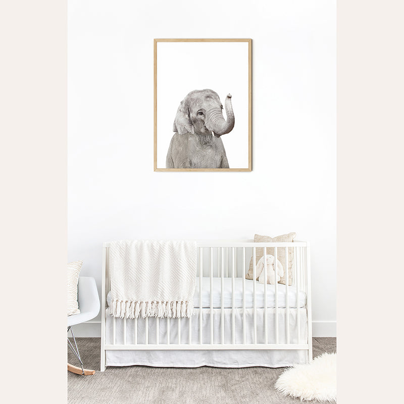 a framed picture of an elephant in a white nursery room