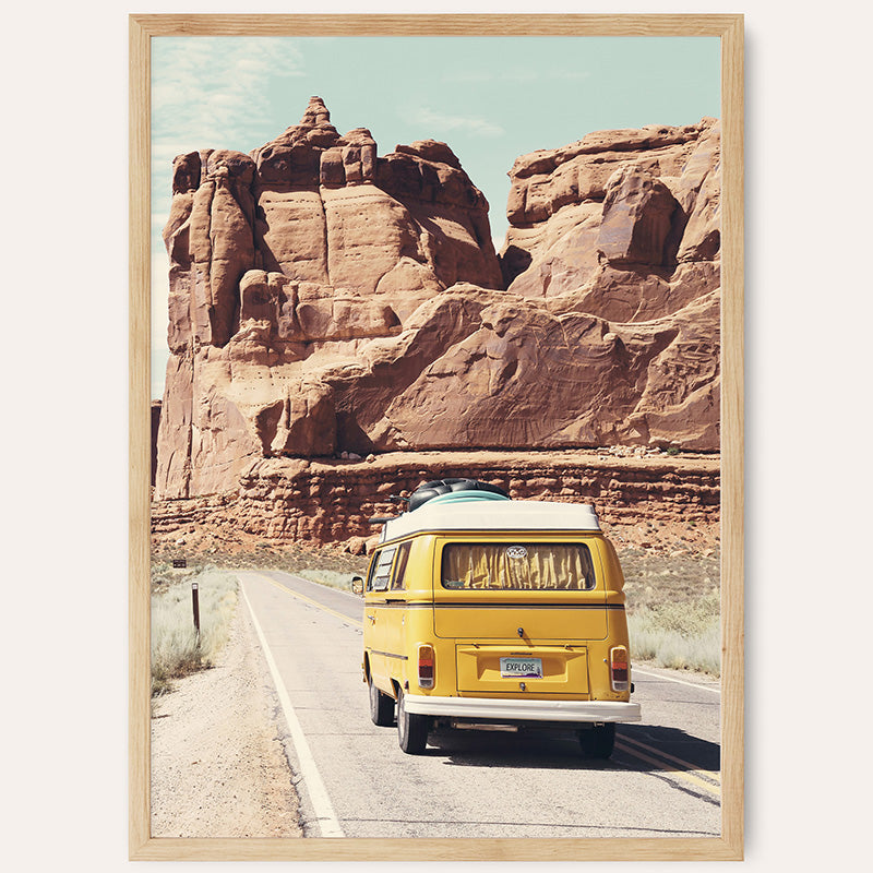 a yellow van driving down a road next to a mountain