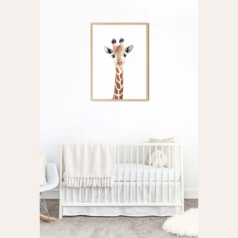 a picture of a giraffe hangs above a crib