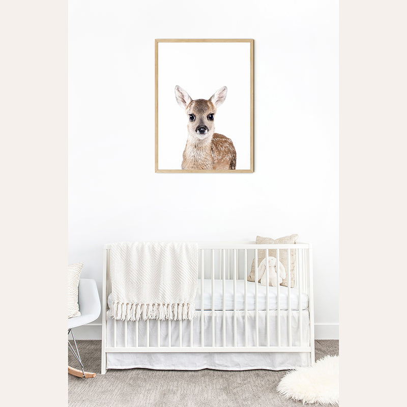 a baby&#39;s room with a white crib and a picture of a deer