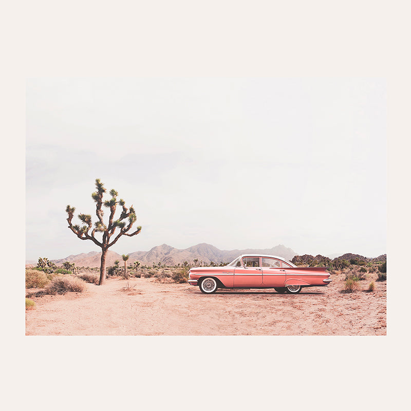 a red car parked in the middle of a desert