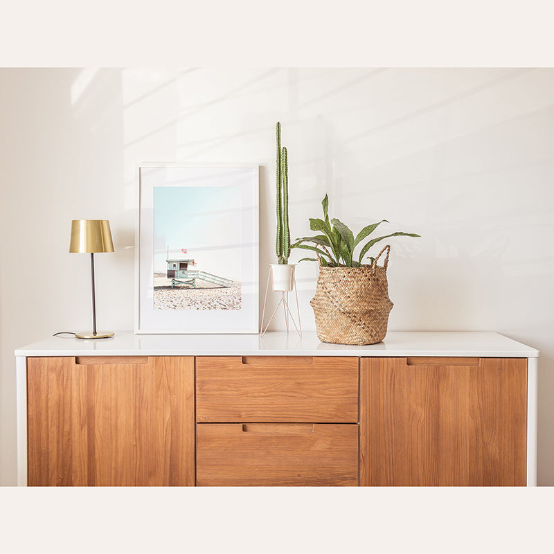 a wooden cabinet with a plant and a picture on top of it