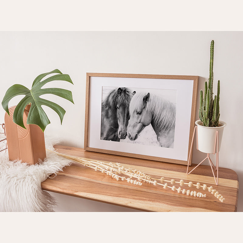 a picture of two horses on a shelf next to a potted plant