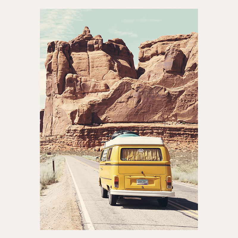 a yellow van driving down a road next to a mountain