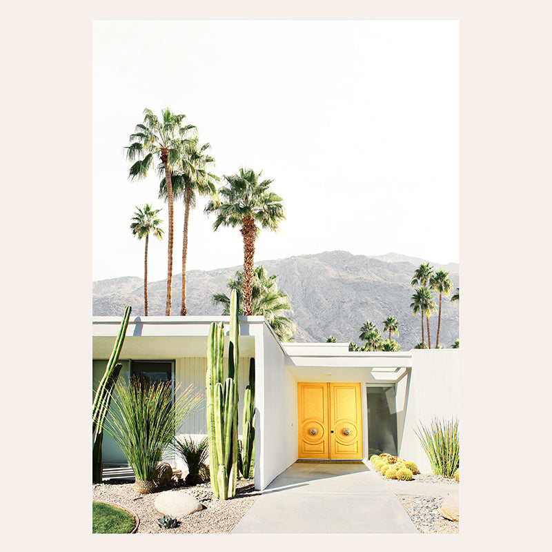 a house with a yellow door surrounded by palm trees