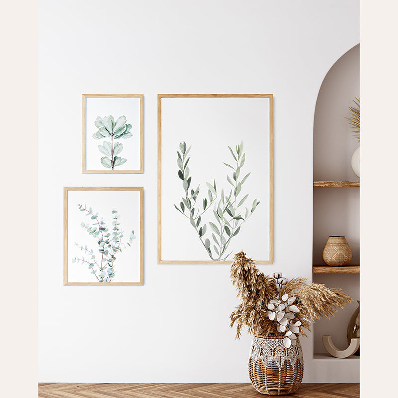 a vase filled with plants next to three framed pictures