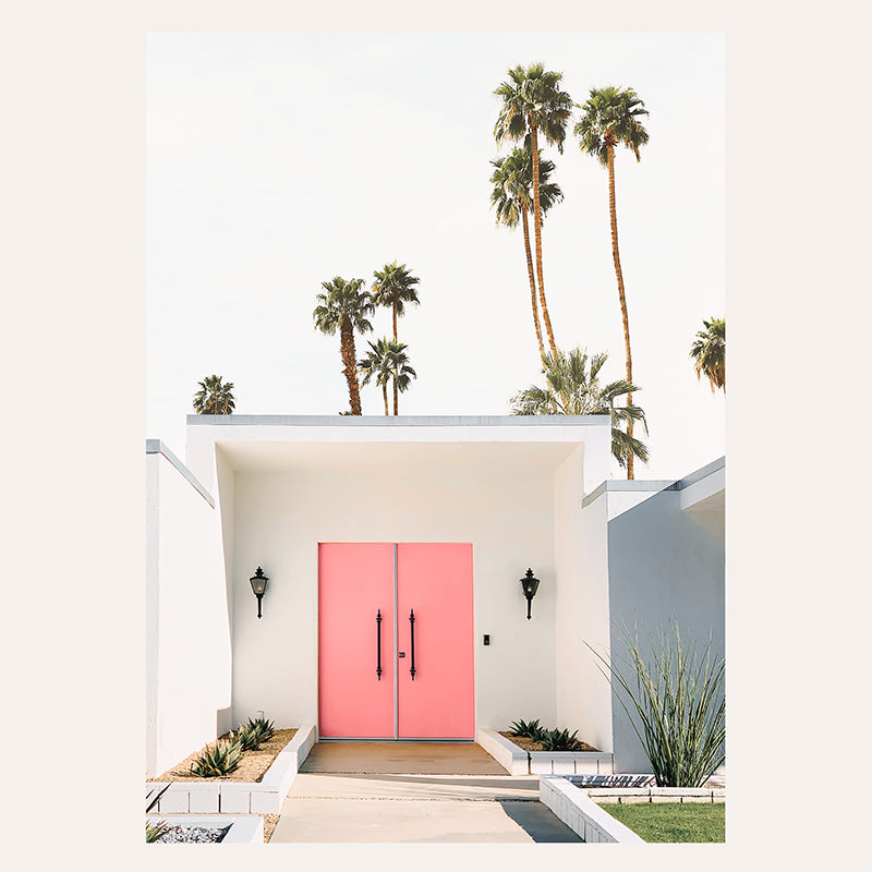 a white house with a pink door and palm trees