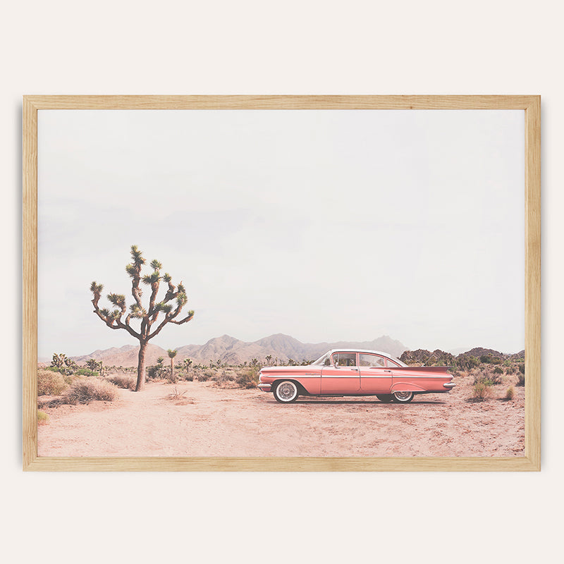 a red car parked in the desert next to a cactus