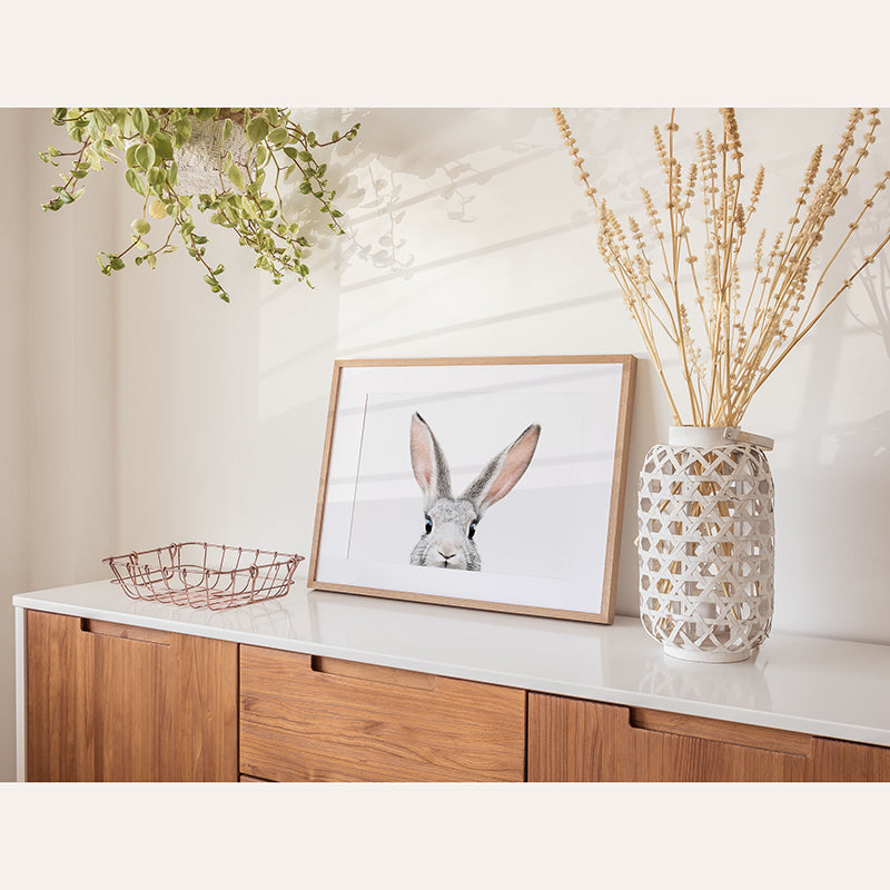 a picture of a rabbit is on a shelf next to a vase