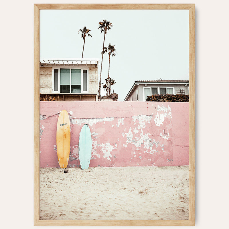 a pink wall with a surfboard leaning against it